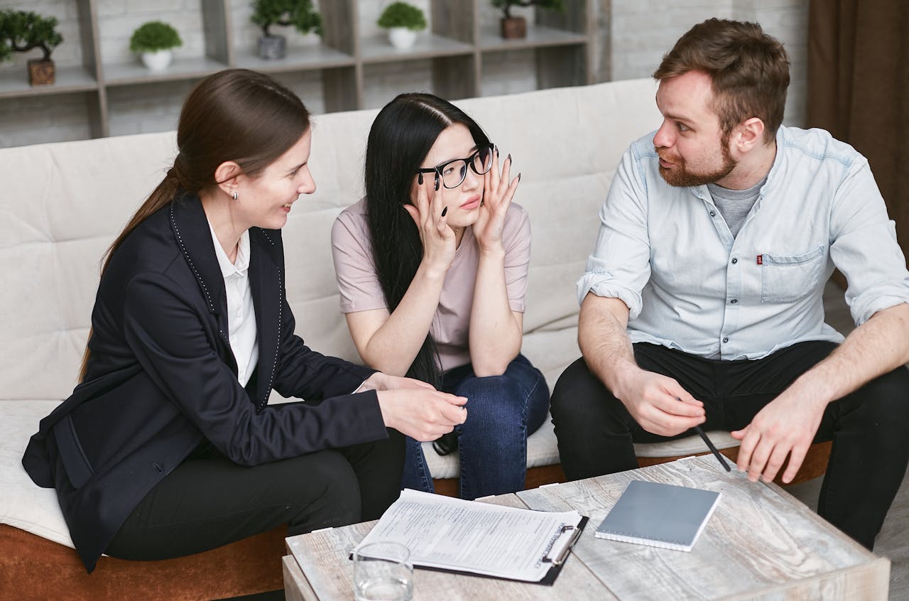 Three adults discussing documents and plans during a collaborative business meeting indoors.